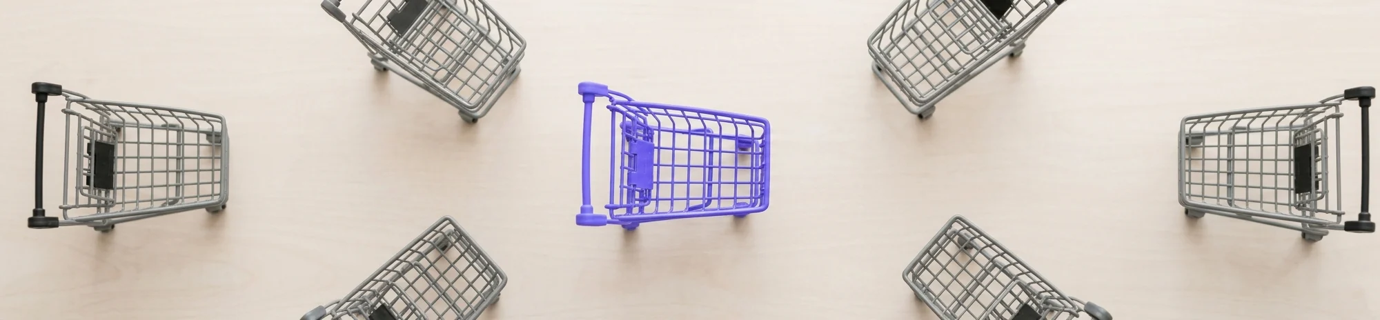 A purple shopping cart standing out among grey shopping carts, illustrating how to reduce cart abandonment