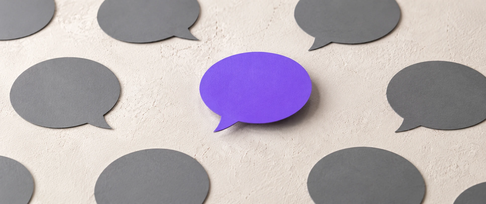 A purple speech bubble standing out among grey speech bubbles, illustrating call to action copy