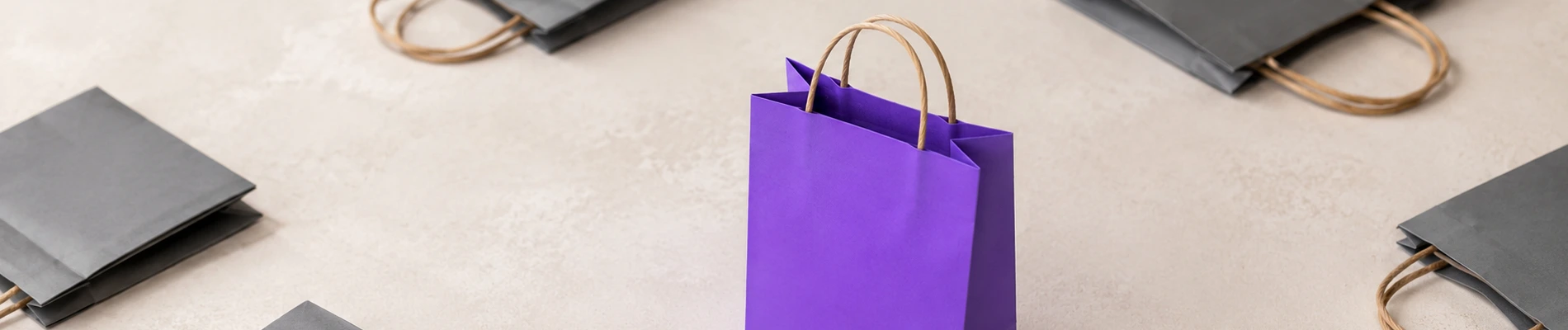 A purple shopping bag standing out among grey bags, illustrating how to make your Add to Cart button stand out